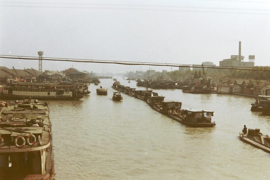 Misty Suzhou canal with stone bridge and whitewashed houses at dawn