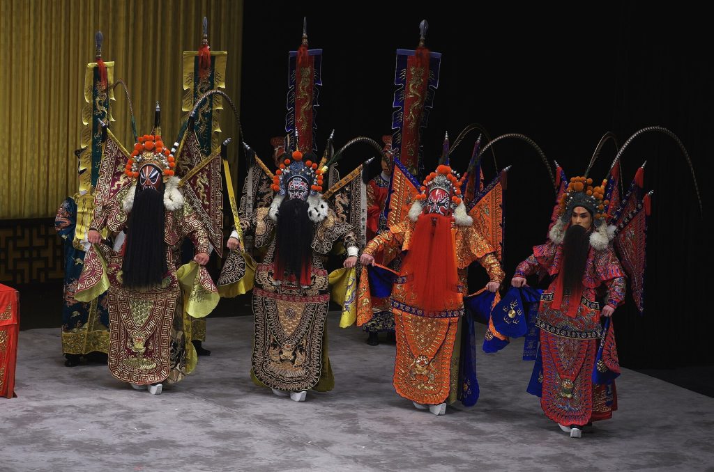 Peking opera performers in ornate costumes and painted faces on stage
