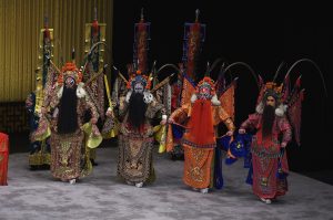 Peking opera performers in ornate costumes and painted faces on stage