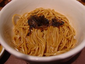 Bowl of Shanghai scallion oil noodles with chopped green onions on a restaurant table