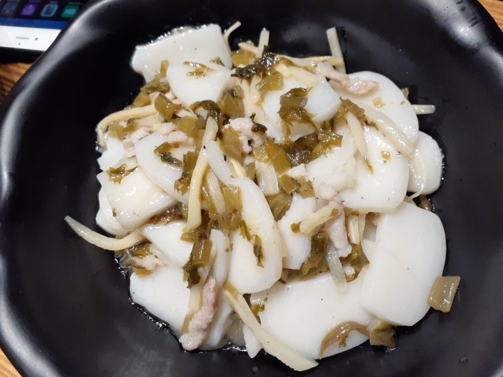 Plate of Shanghai-style stir-fried rice cakes (chao niangao) with shredded pork and preserved greens