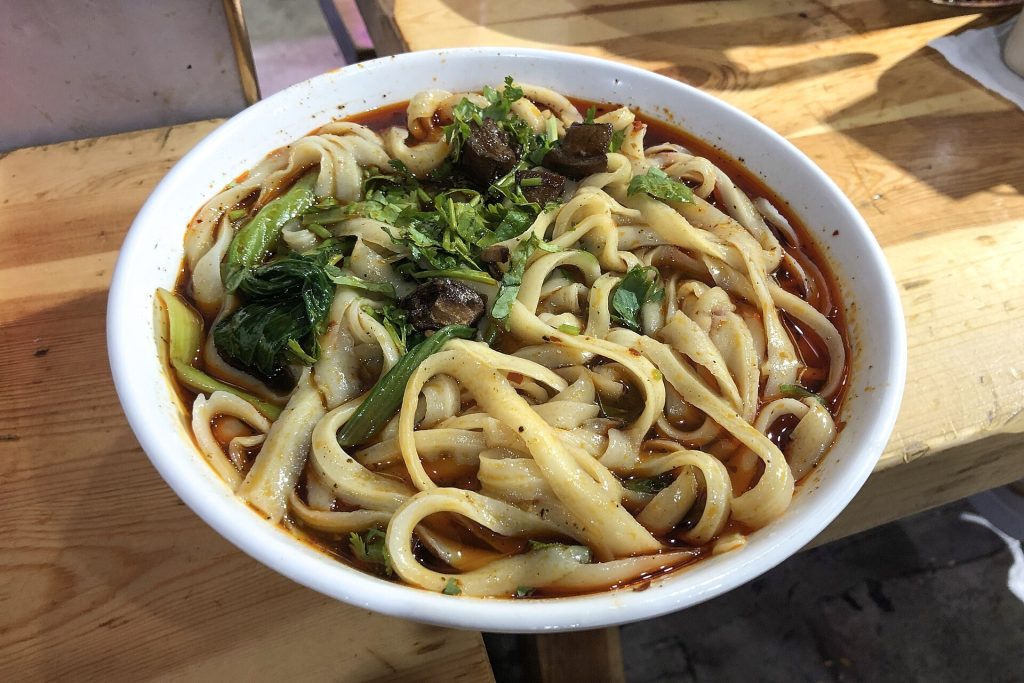 Bowl of Shanxi-style knife-cut noodles (daoxiaomian) with sauce and toppings