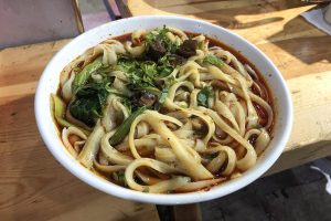 Bowl of Shanxi-style knife-cut noodles (daoxiaomian) with sauce and toppings