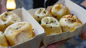 Golden pan-fried shengjianbao pork buns with sesame seeds on a serving plate