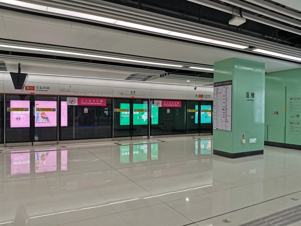 Shenzhen metro platform with bilingual signs and arriving train doors open