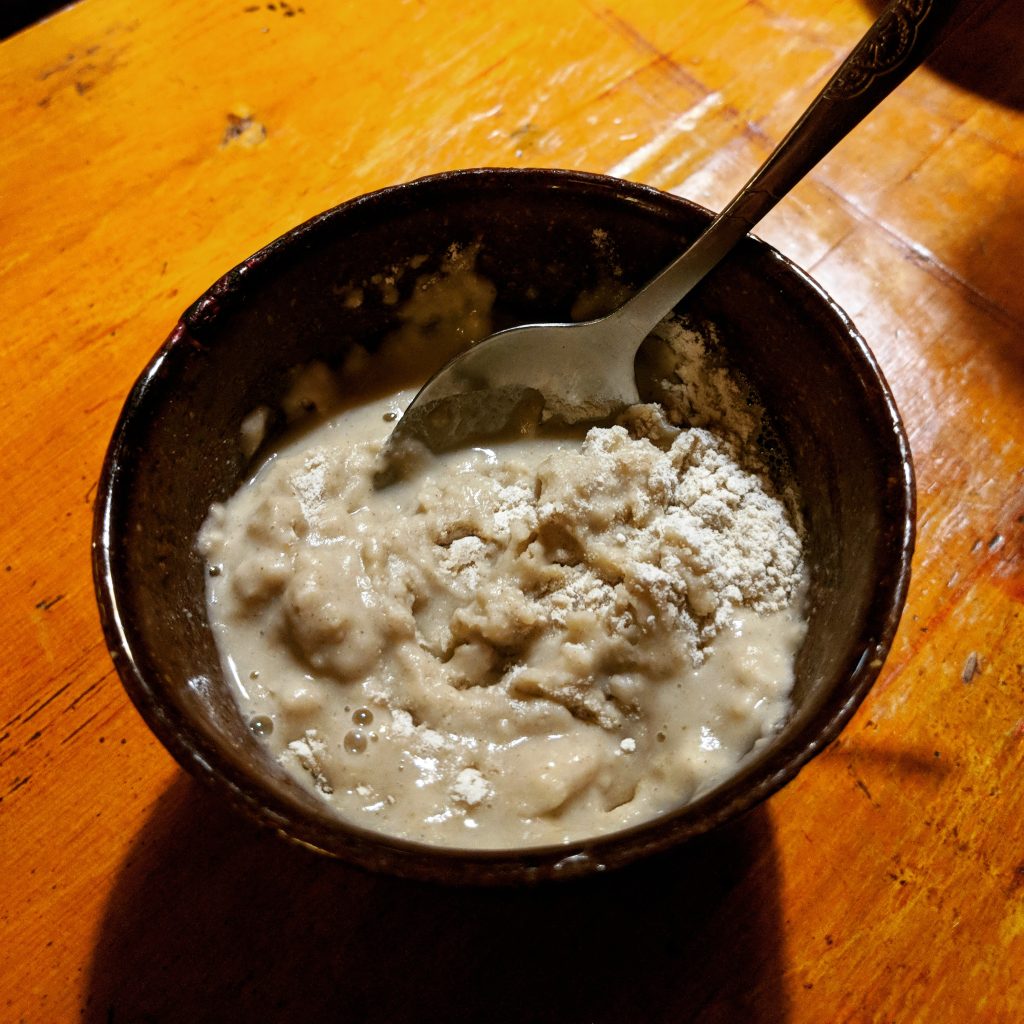 Bowl of Tibetan tsampa roasted barley flour being blended with yak butter tea by hand