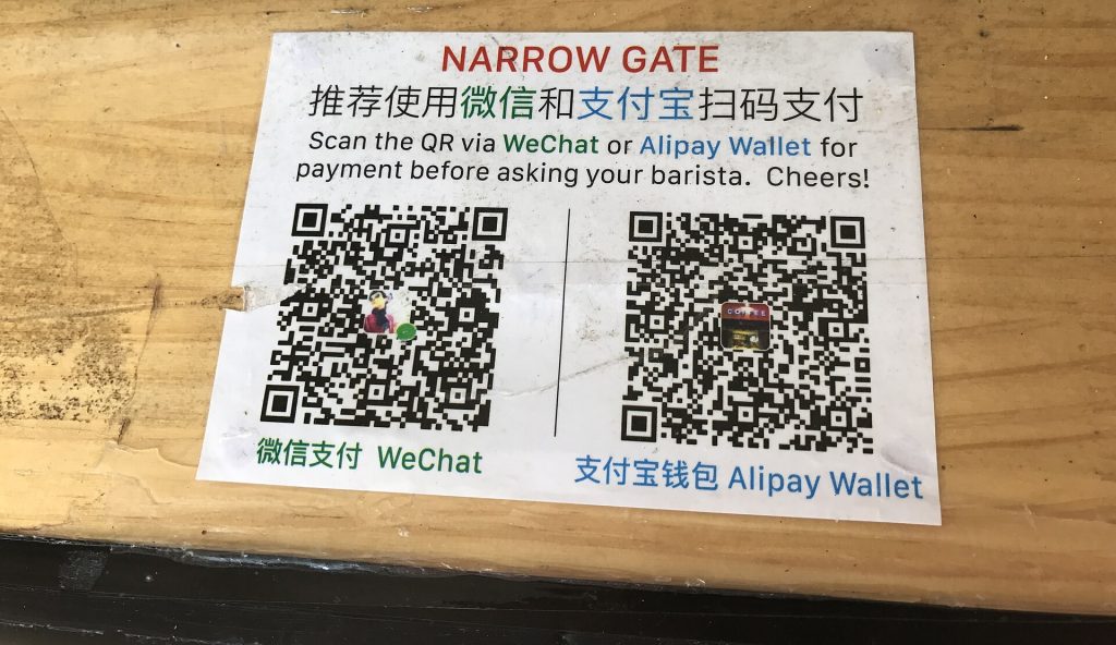 Printed QR codes for Chinese mobile payment apps displayed on a shop counter