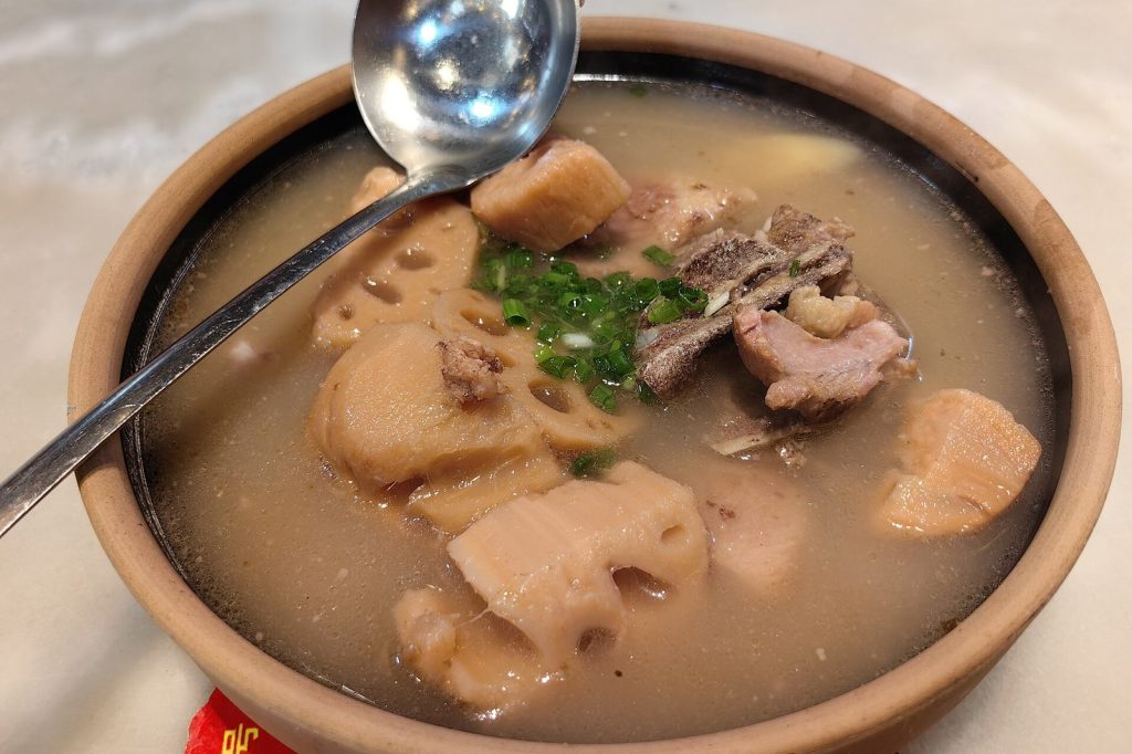 Single-serve clay pot of Wuhan lotus root and pork bone soup with chunks of lotus root, pork and chopped scallions