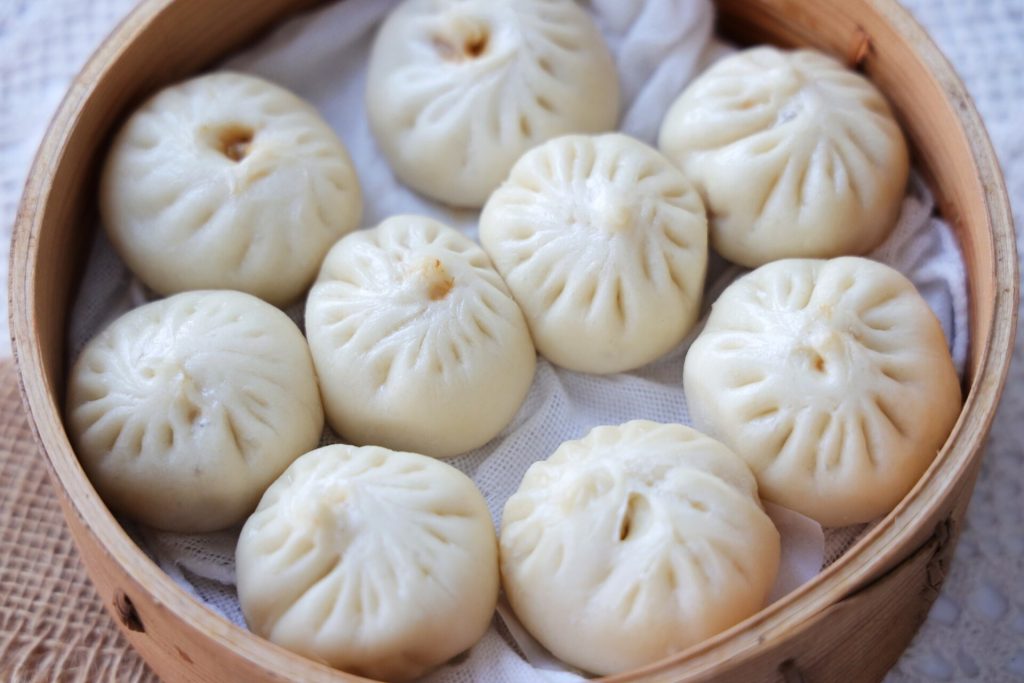 Steamed Shanghai xiaolongbao soup dumplings in a bamboo steamer basket