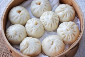 Steamed Shanghai xiaolongbao soup dumplings in a bamboo steamer basket